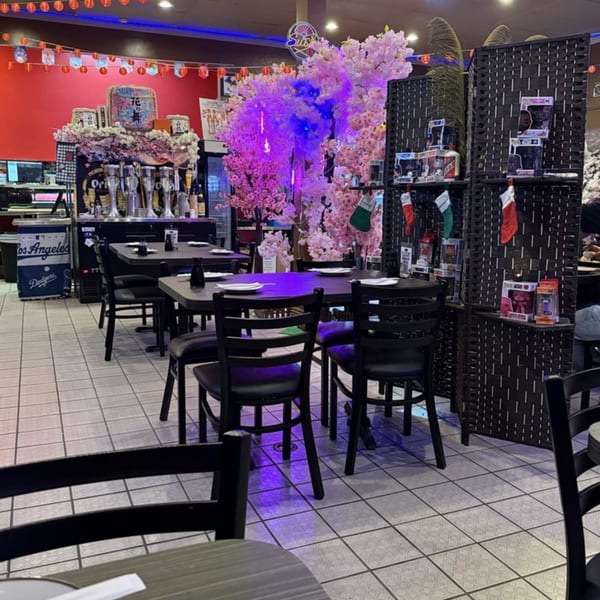 Sushiya restaurant interior with black tables, chairs, pink cherry blossom trees, and red walls.