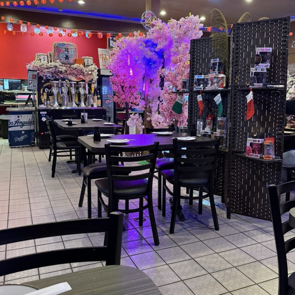 Sushiya restaurant interior with black tables, chairs, pink cherry blossom trees, and red walls.