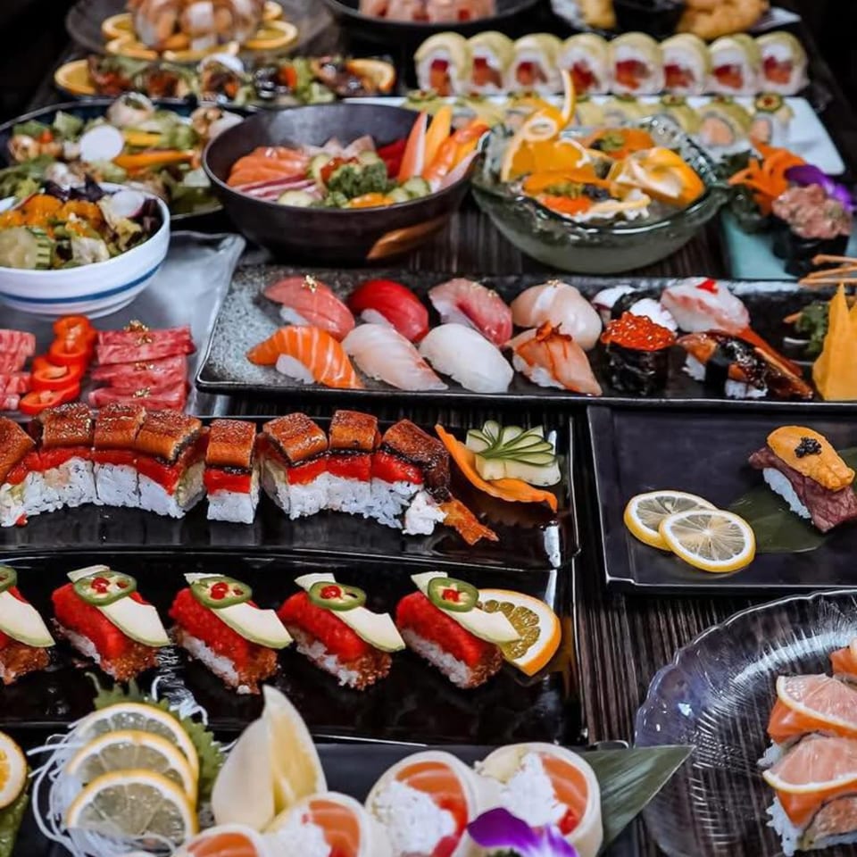 A lavish spread of Japanese cuisine, including various sushi, sashimi, and salads, on a dark table.
