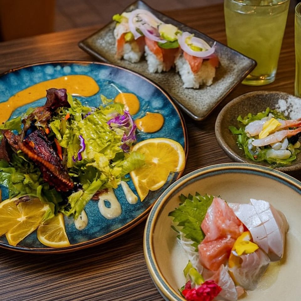 A vibrant Japanese meal featuring sushi, sashimi, salad with salmon, shrimp, and green drinks.
