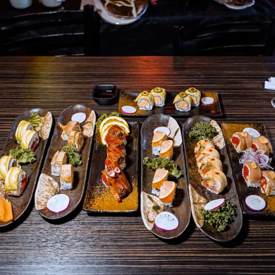 Assortment of colorful sushi rolls, including dragon rolls and maki, on dark plates at Sushiya.